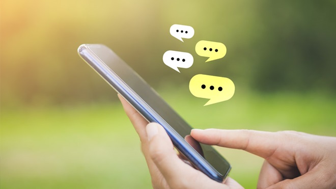 Grande plano de alguém a mexer num smartphone com ícones de fala por cima - alusão à tecnologia Chat GPT