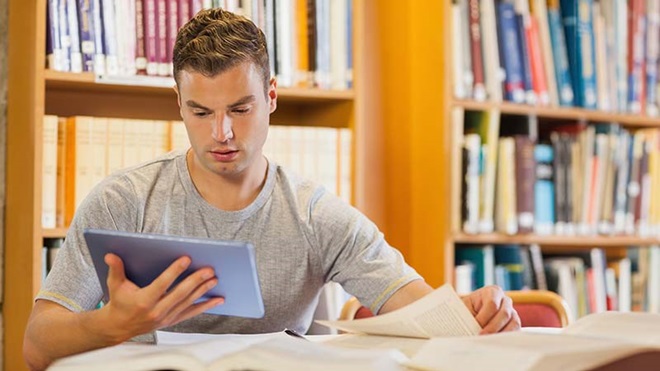 Rapaz a ler livro eletrónico numa biblioteca