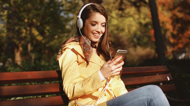 mulher sentada em banco de jardim com o telemovel na mão