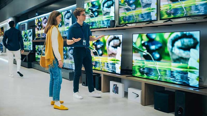 Mulher numa loja de tecnologia escolhe uma smart tv aconselhada por um empregado
