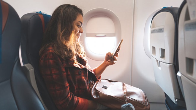 mulher com telemóvel num avião