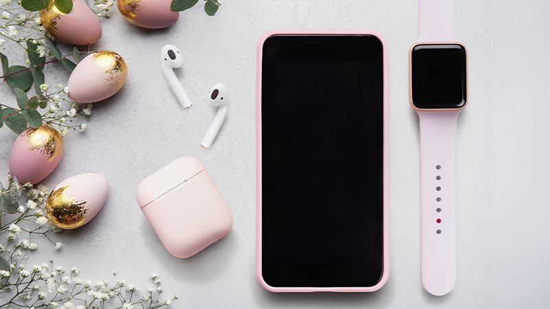 Mesa de Páscoa com pequenos ovos, smartphone, auriculares sem fios e smartwatch