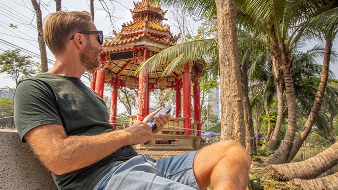 Turista na Tailanda junto a templo a usar telemóvel