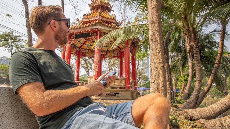 Turista na Tailanda junto a templo a usar telemóvel
