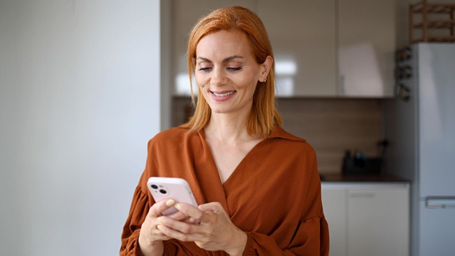 Mulher adulta a ver um telemóvel em casa