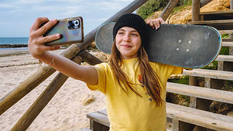 Rapariga a tirar selfie com o skate no ombro