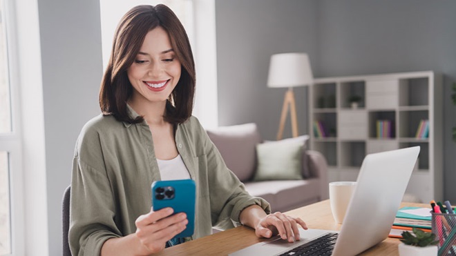 Mulher sentada numa secrtária com um telemóvel iphone na mão