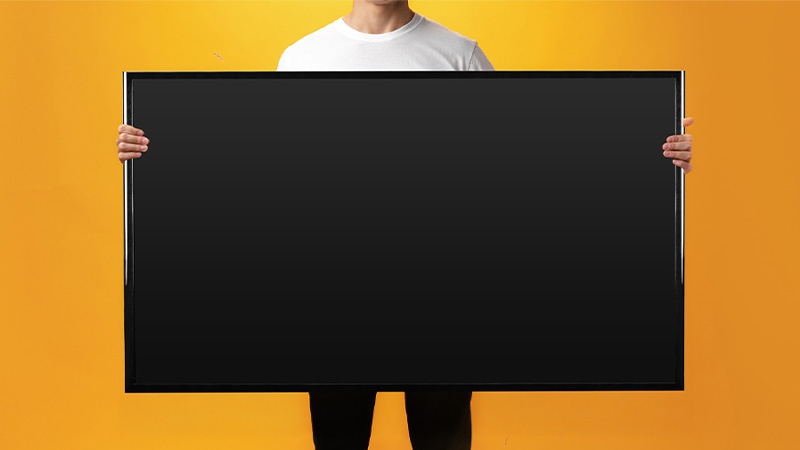 Homem a segurar televisor em fundo amarelo, foto de estúdio