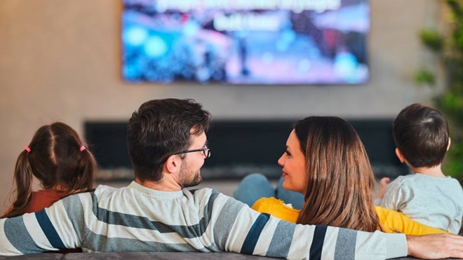Família sentada no sofá a ver televisão