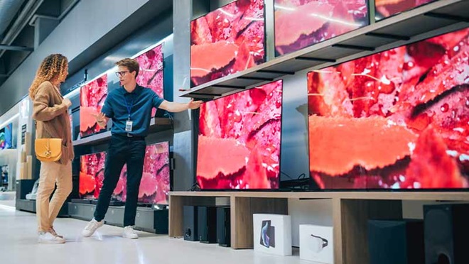 Mulher numa loja a escolher televisores, com um empregado
