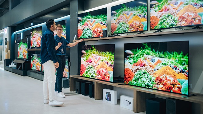 Homem a receber informações de televisores na loja