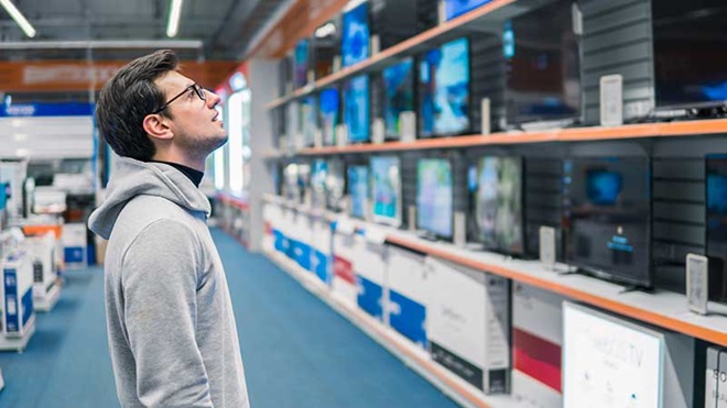 homem a procurar televisões baratas numa loja