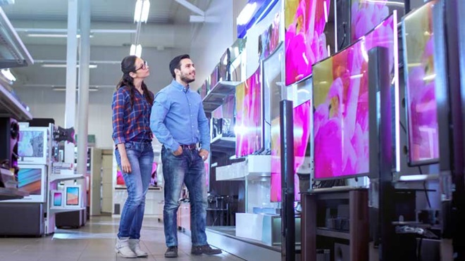 um homem e uma mulher numa loja a escolher entre uma televisão oled ou lcd 
