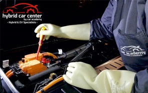 Mecânico com luvas amarelas a reparar a bateria de um carro no hybrid car center, com descontos para titulares do cartão DECO+.